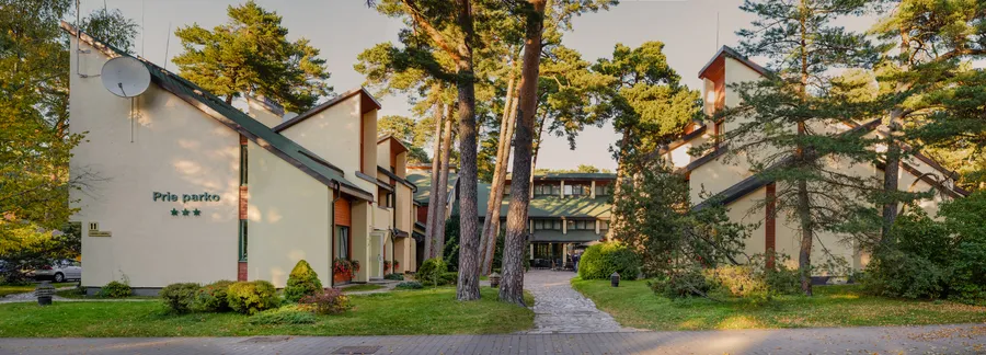 Viešbučio korpusai vakaro saulėje panoraminiame kadre