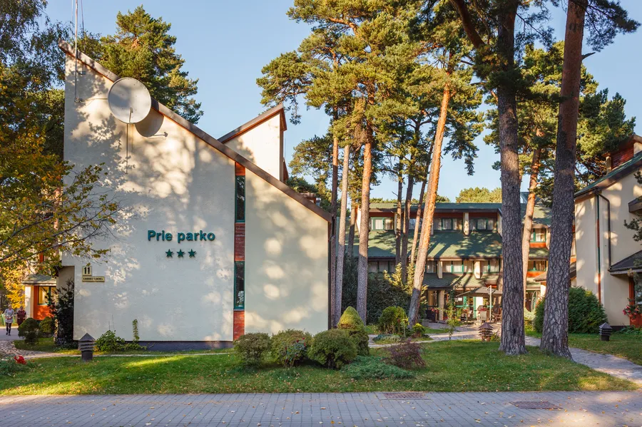 Platus kiemo vaizdas su korpusais tarp pušų