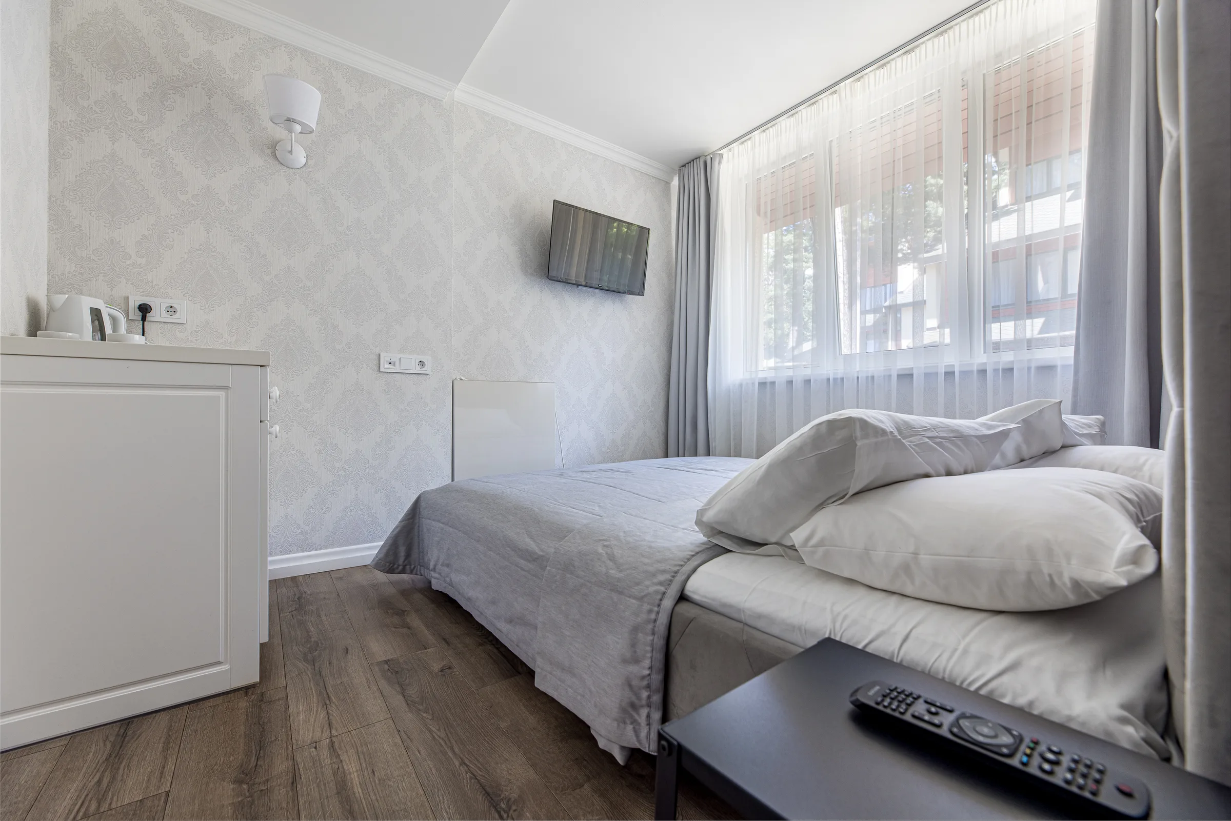 Erdvus dvivietis numeris su lova ir langu į pušyną