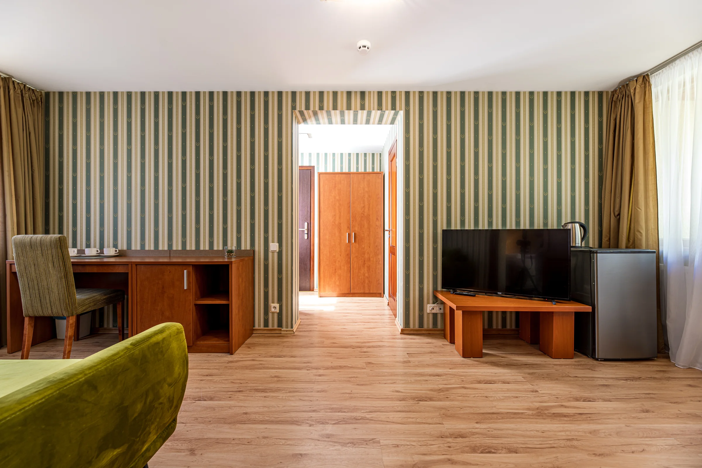 Šeimyninio numerio svetainė: žalia sofa, stalas ir televizorius
