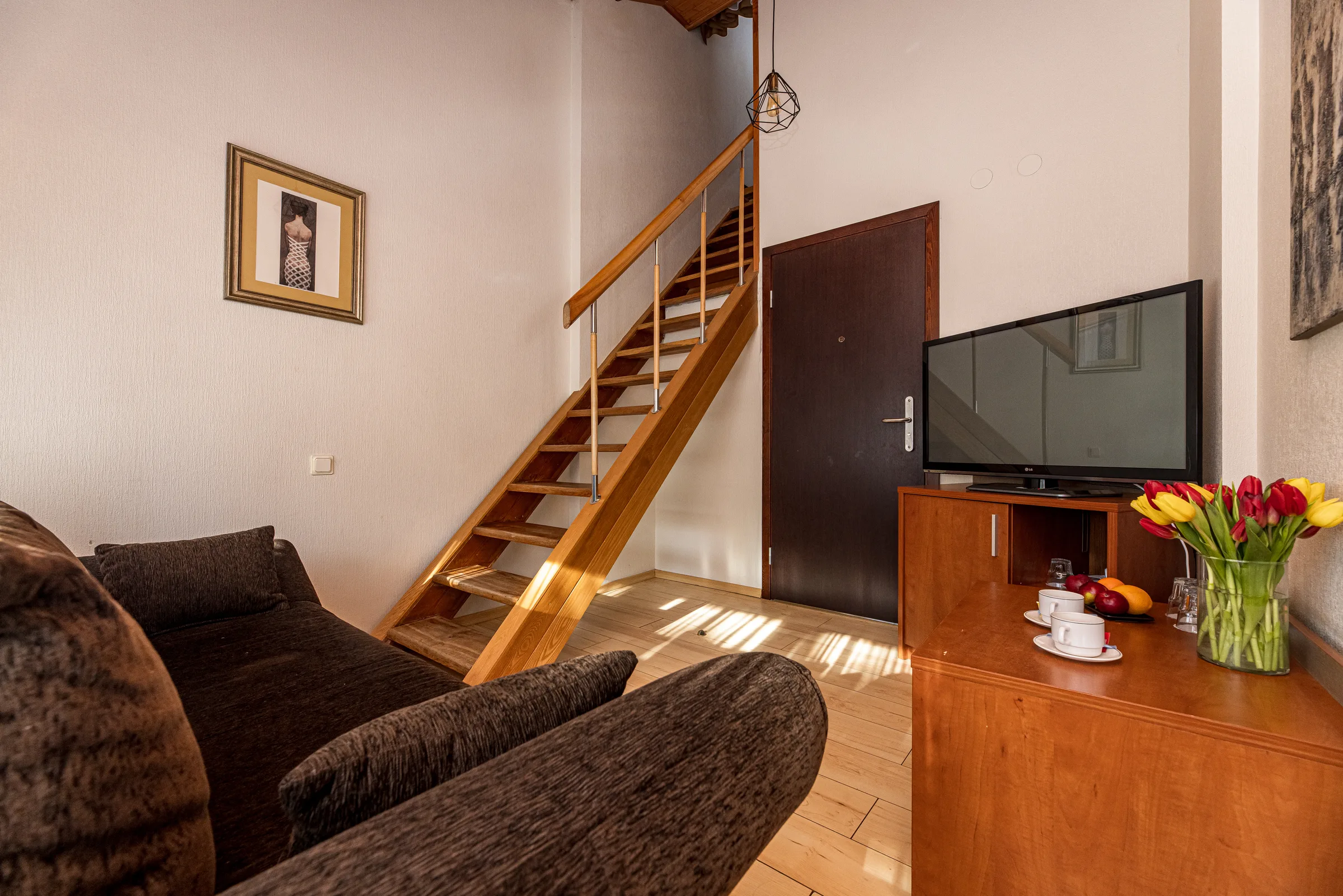 Šeimyninio numerio svetainė su sofa ir laiptais į antrą aukštą