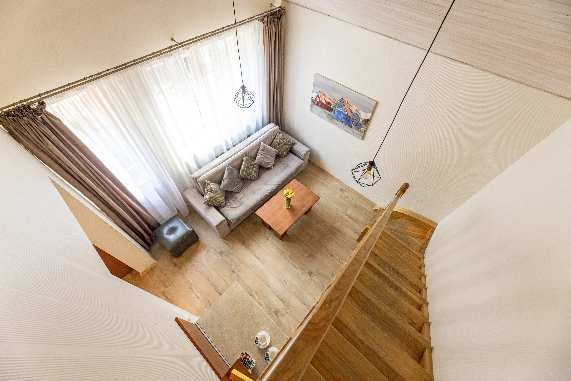 Svetainė su sofa ir laiptais į antrą aukštą
