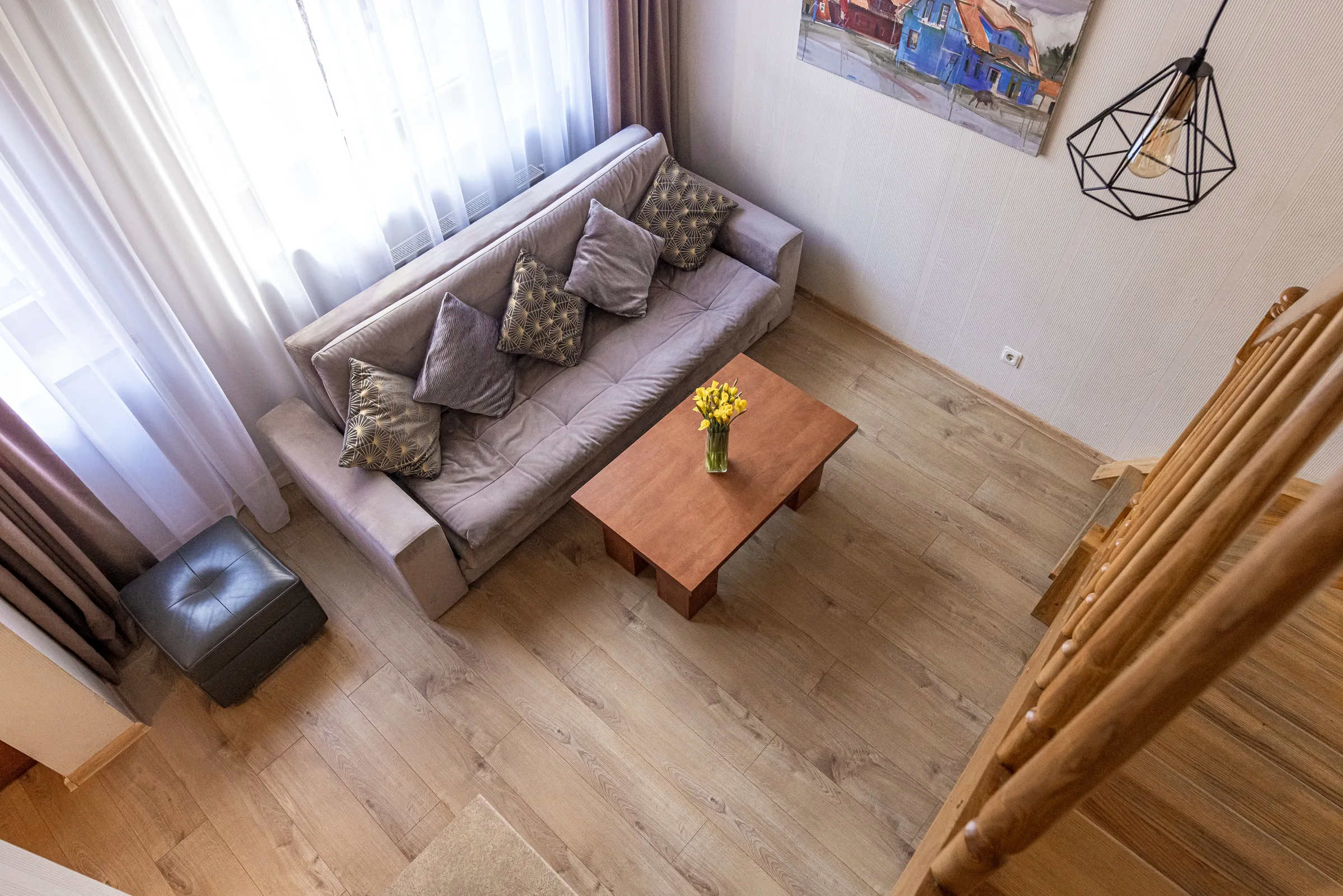 Svetainės kampas su sofa ir mediniais laiptais